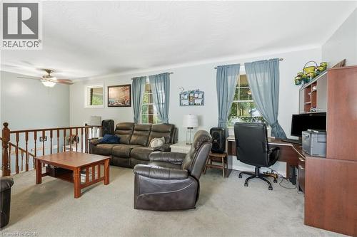Carpeted living area with a built-in office desk, multiple windows, and a ceiling fan with integrated lighting - 1311 W Concession 6 Road, Flamborough, ON 