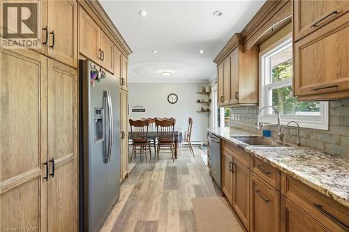Wood-finish cabinetry, stainless steel appliances, speckled stone countertops, subway tile backsplash, and wood-finish flooring - 1311 W Concession 6 Road, Flamborough, ON 