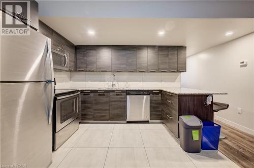 Kitchen featuring wood-finish cabinetry, stainless steel appliances, light-toned countertop, and tile flooring - 338 Albert Street Unit# 114, Waterloo, ON 