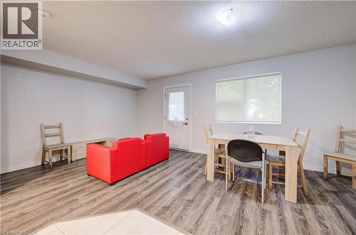 Spacious room with wood-finish flooring, a white paneled door, and a large window with roller shades - 338 Albert Street Unit# 114, Waterloo, ON 