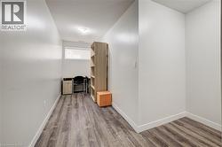 Wood-finish flooring, white walls, and a single window offering natural light - 
