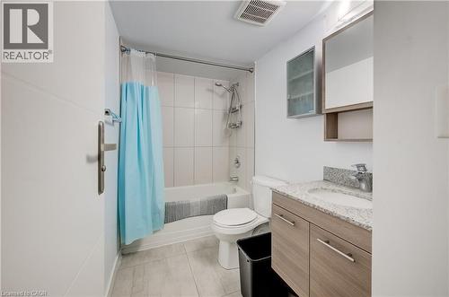 White subway tile shower surround, integrated bathtub, light wood-finish vanity with drawer storage, speckled stone-look countertop, and a mirrored medicine cabinet - 338 Albert Street Unit# 114, Waterloo, ON 