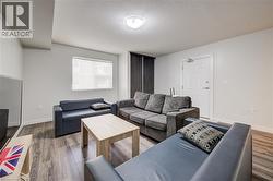 Room featuring wood-finish flooring, white walls, and a window with roller blinds - 