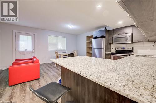 Kitchen featuring light-toned countertops, wood-finish cabinetry, stainless steel appliances, and a white tile backsplash - 338 Albert Street Unit# 114, Waterloo, ON 