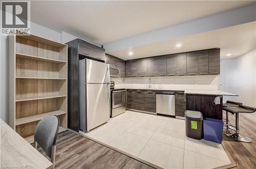Kitchen with stainless steel appliances, dark wood-finish cabinetry, light-toned countertop, and recessed lighting - 338 Albert Street Unit# 114, Waterloo, ON 