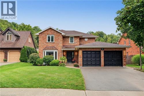 Brick exterior with a gabled roofline, bay window, and a two-car attached garage - 141 Race Street, Paris, ON 