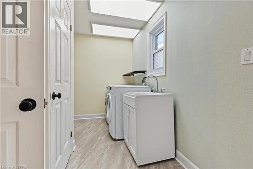 Laundry area featuring a utility sink with a white cabinet, wood-finish flooring, and a window with blinds - 141 Race Street, Paris, ON 