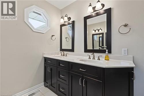 Dual vanity with dark wood-finish cabinetry, integrated sinks, and polished chrome fixtures - 141 Race Street, Paris, ON 