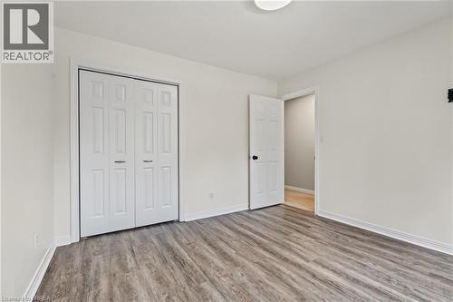 Wood-finish flooring, white bi-fold closet doors, white interior door, and a flush mount ceiling light - 141 Race Street, Paris, ON 