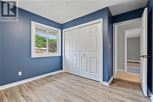 Wood-finish flooring, white bi-fold closet doors, white trim, and a white window frame - 141 Race Street, Paris, ON 