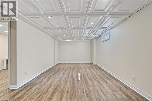 Recessed lighting illuminates the wood-finish flooring in this versatile space, featuring a white coffered ceiling and a window providing natural light - 141 Race Street, Paris, ON 