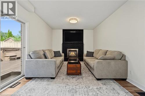 Sliding glass door, wood-finish flooring, black tile fireplace surround, built-in fireplace, and overhead flush-mount lighting - 141 Race Street, Paris, ON 