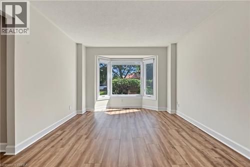 Spacious room featuring wood-finish flooring, light-toned walls, and a prominent bay window - 141 Race Street, Paris, ON 