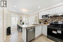 White cabinetry, stainless steel appliances, mosaic tile backsplash, recessed lighting, and a kitchen island with integrated sink - 