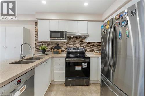 White cabinetry with chrome hardware, stone countertops, stainless steel appliances, and a mosaic tile backsplash - 123 Brickyard Way, Brampton, ON 