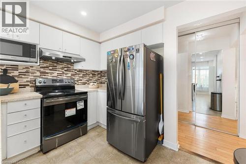 Kitchen featuring white cabinetry, stone-look countertops, a mosaic tile backsplash, and stainless steel appliances - 123 Brickyard Way, Brampton, ON 