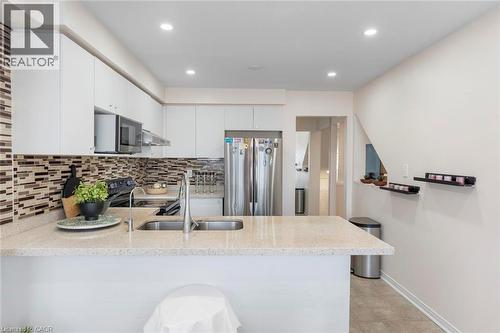 Modern kitchen featuring white cabinetry, a light-toned countertop, a tile backsplash, stainless steel appliances, and recessed lighting - 123 Brickyard Way, Brampton, ON 