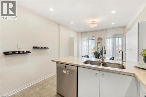 Kitchen island featuring a double basin sink, stainless steel dishwasher, and light-toned countertop - 123 Brickyard Way, Brampton, ON 