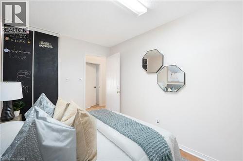 White walls with wood-finish flooring, featuring a built-in chalkboard wall, two octagonal wall mirrors, and a white interior door - 123 Brickyard Way, Brampton, ON 