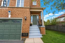 Brick exterior with a covered porch entry, a paneled garage door, and a concrete walkway - 