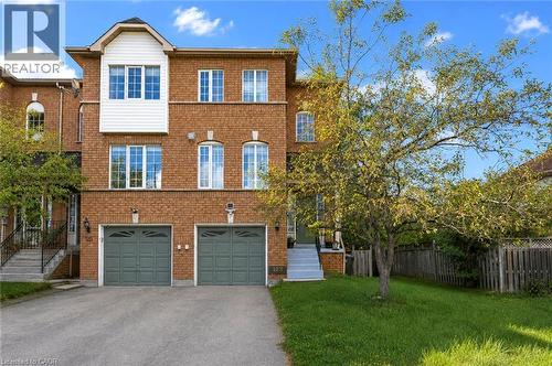 Brick exterior with light-colored siding accents, two-car garage, established front yard tree, and an asphalt driveway - 123 Brickyard Way, Brampton, ON 