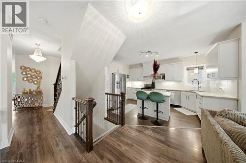Open concept layout featuring wood-finish flooring, a contemporary kitchen with white cabinetry, stainless steel appliances, and a central island with seating - 167 Broadoaks Drive, Cambridge, ON 