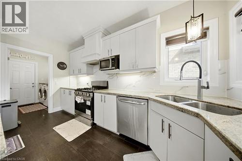 Kitchen featuring white cabinetry, stainless steel appliances, granite countertops, an undermount double-basin sink, and dark wood-finish flooring - 167 Broadoaks Drive, Cambridge, ON 