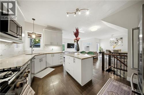 Kitchen featuring light cabinetry, a central island with a stone countertop, an integrated microwave, and a stainless steel oven - 167 Broadoaks Drive, Cambridge, ON 