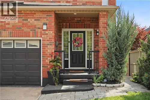 Brick exterior, covered entry, black paneled front door with glass inserts, black garage door with upper window panels, and paver walkway - 167 Broadoaks Drive, Cambridge, ON 