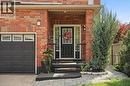 Brick exterior, covered entry, black paneled front door with glass inserts, black garage door with upper window panels, and paver walkway - 167 Broadoaks Drive, Cambridge, ON 