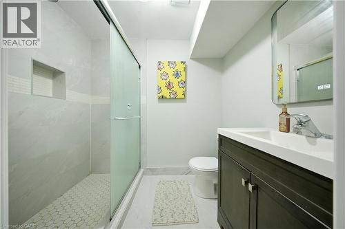 Walk-in shower with sliding glass door, white hexagonal tile flooring, and integrated shower niche - 167 Broadoaks Drive, Cambridge, ON 