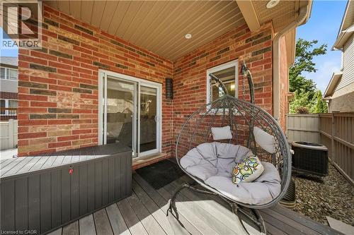 Rear patio featuring brick exterior, sliding glass door, composite decking, and a privacy fence - 167 Broadoaks Drive, Cambridge, ON 