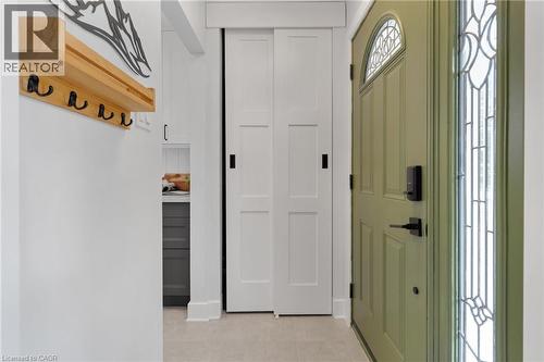 Sage green entry door with arched transom window, leaded glass sidelight, bi-fold panel doors, and tile flooring - 477 Kingscourt Drive Unit# B, Waterloo, ON 
