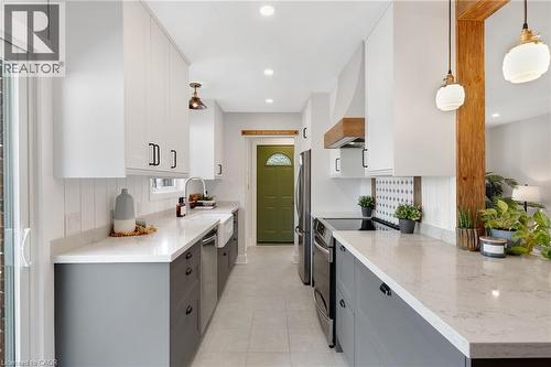 Two-tone cabinetry with white upper and gray lower cabinets, light-toned countertops, recessed and pendant lighting, and stainless steel appliances - 477 Kingscourt Drive Unit# B, Waterloo, ON 