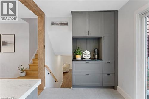 Built-in gray cabinetry with black hardware, black countertop, light wood staircase, and wood-finish beam - 477 Kingscourt Drive Unit# B, Waterloo, ON 
