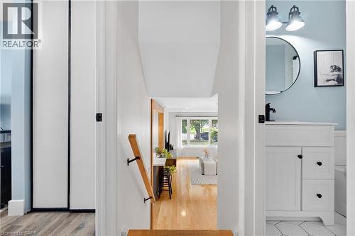 Hardwood flooring, painted white cabinetry, matte black hardware, hexagonal floor tiling, and a circular mirror - 477 Kingscourt Drive Unit# B, Waterloo, ON 