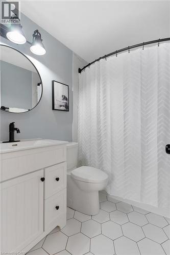 White hexagonal tile flooring, white vanity with black hardware, black faucet, circular mirror, and track lighting - 477 Kingscourt Drive Unit# B, Waterloo, ON 