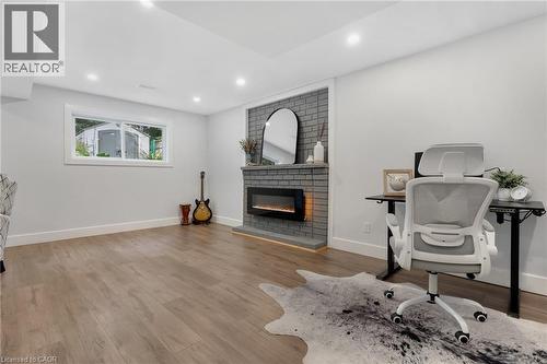 Recessed lighting, wood-finish flooring, brick-surround fireplace with hearth, and a window with white trim - 477 Kingscourt Drive Unit# B, Waterloo, ON 