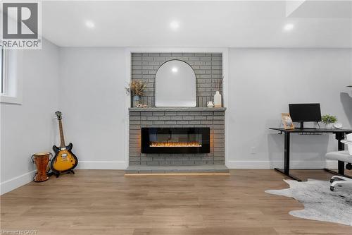 Recessed lighting, wood-finish flooring, and a modern fireplace with a grey brick surround - 477 Kingscourt Drive Unit# B, Waterloo, ON 