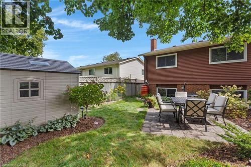 Spacious rear yard featuring a paved patio, mature trees, and a detached storage shed with a skylight - 477 Kingscourt Drive Unit# B, Waterloo, ON 