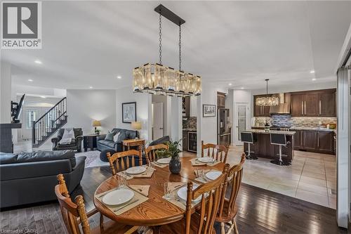 Open-concept main level featuring a dining area with wood-finish flooring and a contemporary chandelier - 249 Woodway Trail, Simcoe, ON 