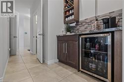 Built-in wet bar featuring dark wood-finish cabinetry, stone-finish countertop, under-mount sink, and a beverage refrigerator - 