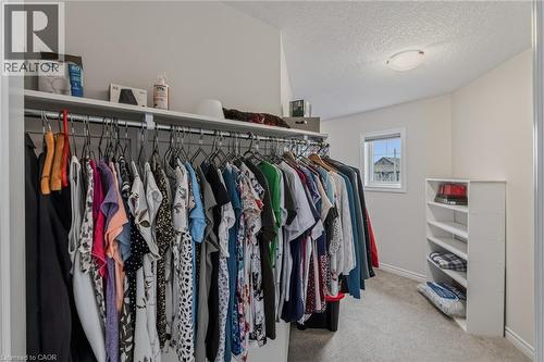 Walk-in closet featuring built-in shelving, hanging rods, an integrated window, and overhead lighting - 249 Woodway Trail, Simcoe, ON 