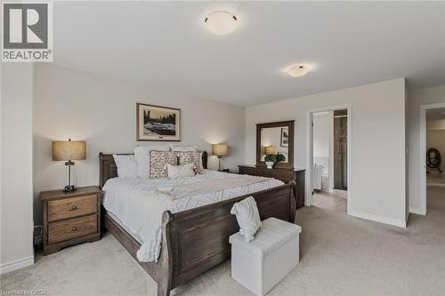 Carpeted bedroom with a built-in ceiling light fixture and an en-suite bathroom featuring a tiled floor and shower enclosure - 249 Woodway Trail, Simcoe, ON 