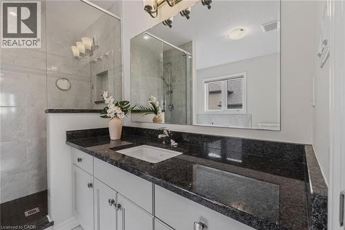 Bathroom vanity with a dark speckled countertop, undermount sink, and chrome faucet - 249 Woodway Trail, Simcoe, ON 