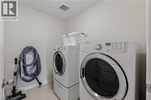 Dedicated laundry space featuring neutral wall tones and tile flooring - 249 Woodway Trail, Simcoe, ON 