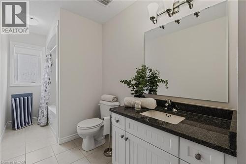 Bathroom featuring a white vanity with dark countertop, undermount sink, and large wall-mounted mirror - 249 Woodway Trail, Simcoe, ON 