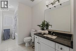 Bathroom featuring a white vanity with dark countertop, undermount sink, and large wall-mounted mirror - 