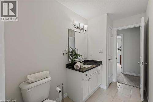 Bathroom vanity with a dark countertop and white cabinetry - 249 Woodway Trail, Simcoe, ON 