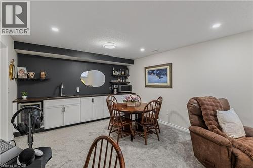 Finished basement entertainment space featuring a wet bar with white cabinetry, dark countertop, and integrated sink - 249 Woodway Trail, Simcoe, ON 